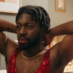 black man with plaits in a sequenced red dress